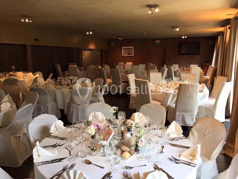 Salle de réception élégamment décorée avec des tables rondes dressées pour un événement formel.