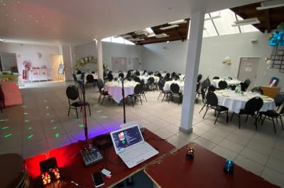 Salle décorée pour un événement avec tables alignées, nappes blanches, compositions florales et allée centrale ornée.