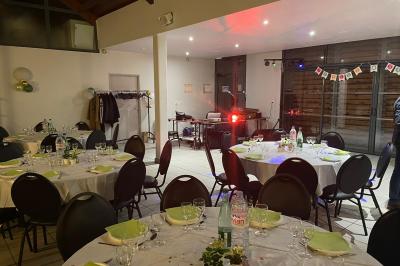 Salle décorée pour un événement avec tables alignées, nappes blanches, compositions florales et allée centrale ornée.