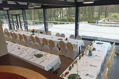 Salle décorée pour un événement avec tables alignées, nappes blanches, compositions florales et allée centrale ornée.