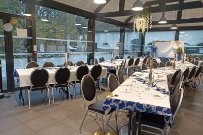 Salle décorée pour un événement avec tables alignées, nappes blanches, compositions florales et allée centrale ornée.