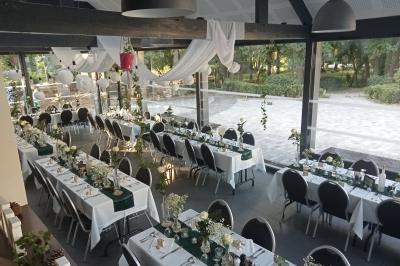 Salle décorée pour un événement avec tables alignées, nappes blanches, compositions florales et allée centrale ornée.