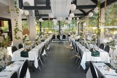 Salle décorée pour un événement avec tables alignées, nappes blanches, compositions florales et allée centrale ornée.
