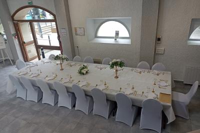 Salle décorée pour un événement avec tables alignées, nappes blanches, compositions florales et allée centrale ornée.