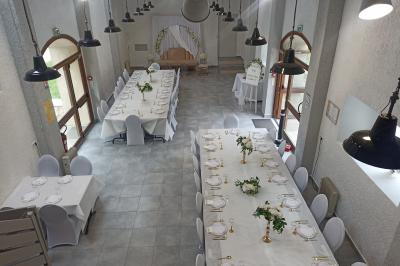 Salle décorée pour un événement avec tables alignées, nappes blanches, compositions florales et allée centrale ornée.