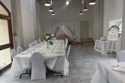 Salle décorée pour un événement avec tables alignées, nappes blanches, compositions florales et allée centrale ornée.
