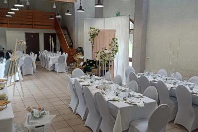 Salle décorée pour un événement avec tables alignées, nappes blanches, compositions florales et allée centrale ornée.