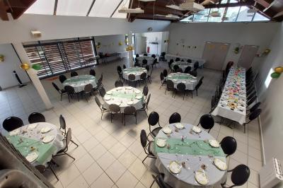 Salle décorée pour un événement avec tables alignées, nappes blanches, compositions florales et allée centrale ornée.