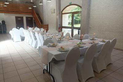 Salle décorée pour un événement avec tables alignées, nappes blanches, compositions florales et allée centrale ornée.