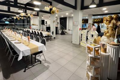 Salle décorée pour un événement avec tables alignées, nappes blanches, compositions florales et allée centrale ornée.