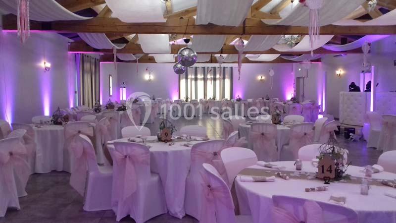 Location salle Saint-Rémy-de-Provence (Bouches-du-Rhône) - Mas de Jonquerolles #6 Salle de réception décorée avec des tables rondes, nappes blanches, chaises ornées de nœuds roses et éclairage violet.
