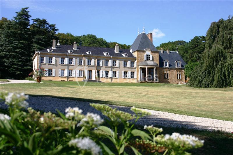 Grande maison de style traditionnel entourée d'un parc verdoyant avec des fleurs au premier plan.