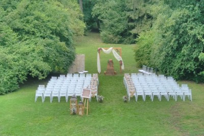 Miniature Location salle Soisy-sur-École (Essonne) - Domaine du Moulin des Noues #26 Disposition de chaises blanches en extérieur autour d'une allée menant à une petite scène sous une tente blanche.