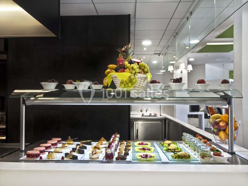 Buffet avec desserts variés, fruits frais et verrines, présenté sous une vitrine dans un espace lumineux.