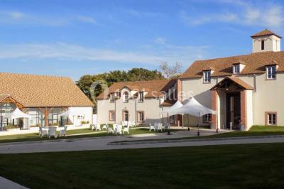 Miniature Location salle Bouray-sur-Juine (Essonne) - Domaine De Frémigny #11 Vue aérienne d'un bâtiment en forme de cour rectangulaire avec des toits en tuiles, entouré de champs et d'arbres.