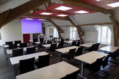 Miniature Location salle Bouray-sur-Juine (Essonne) - Domaine De Frémigny #3 Vue aérienne d'un bâtiment en forme de cour rectangulaire avec des toits en tuiles, entouré de champs et d'arbres.