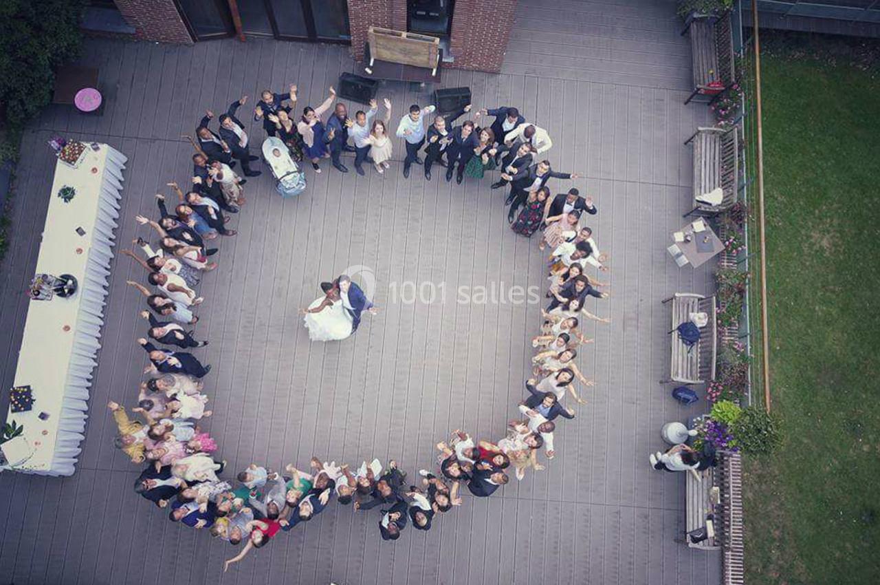 Vue aérienne d'un couple dansant au centre d'un cercle formé par des invités sur une terrasse en extérieur.