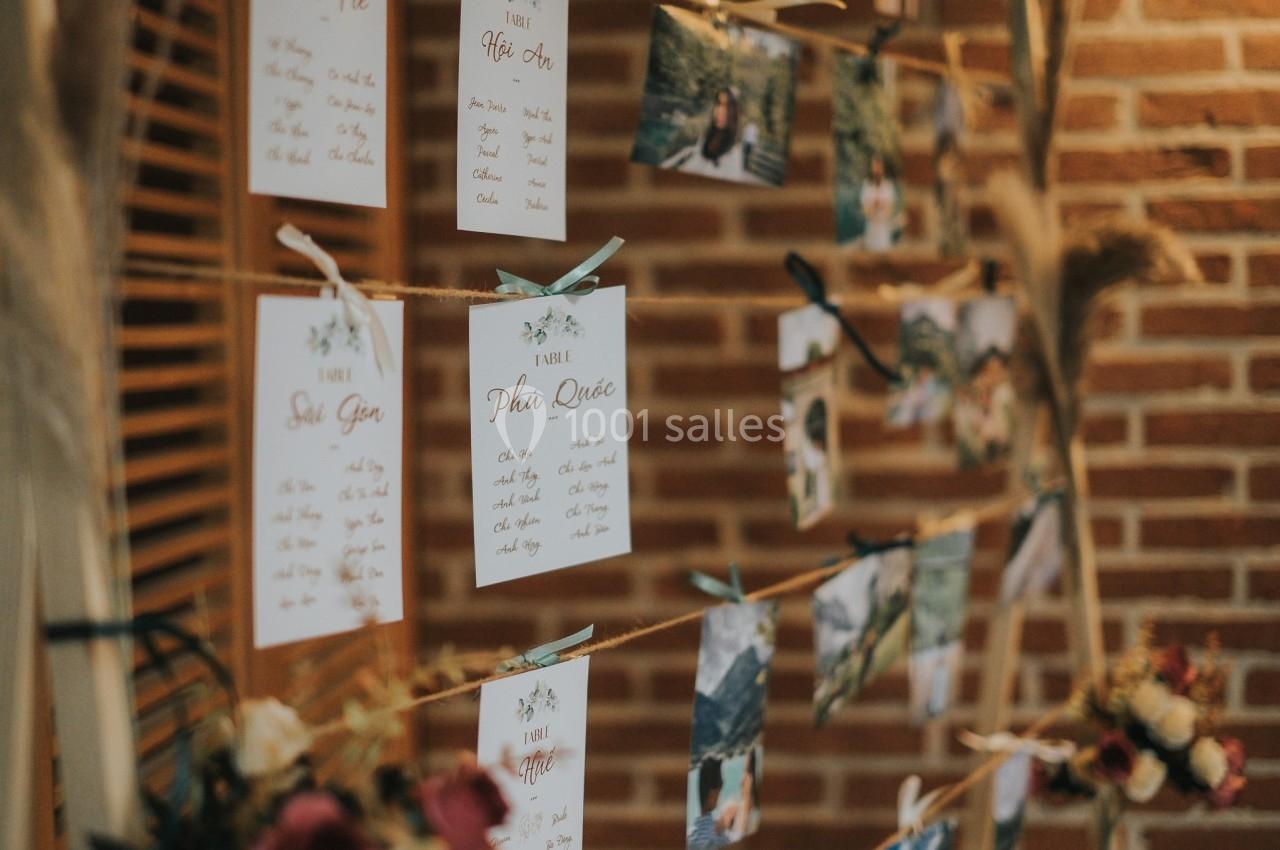 Cartes et photos suspendues sur des cordes, accrochées à des pinces en bois, devant un mur de briques.