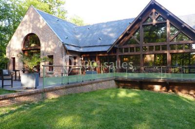 Miniature Location salle Janvry (Essonne) - Golf de Marivaux #13 Maison en bois éclairée la nuit, entourée d'arbres illuminés, sous un ciel nuageux avec la lune visible.
