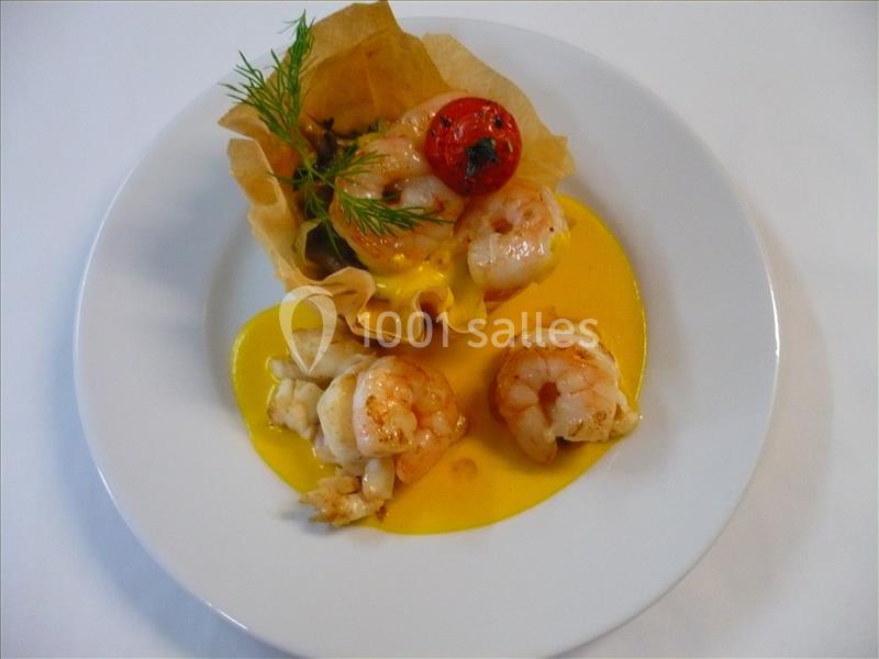 Assiette avec crevettes, sauce jaune, tomate cerise et panier croustillant garni, décorée d'une branche d'aneth.