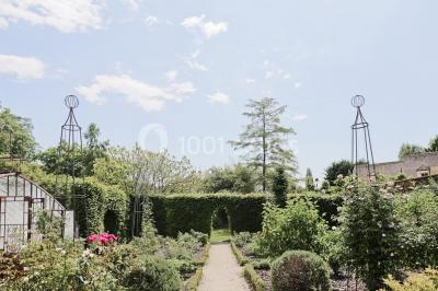 Miniature Location salle Verderonne (Oise) - Domaine de Verderonne #20 Serre illuminée au crépuscule, entourée de murs en pierre et d'arbres, avec une tour en arrière-plan.