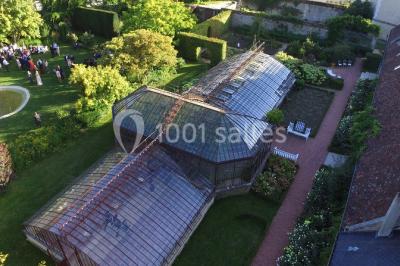 Miniature Location salle Verderonne (Oise) - Domaine de Verderonne #5 Serre illuminée au crépuscule, entourée de murs en pierre et d'arbres, avec une tour en arrière-plan.