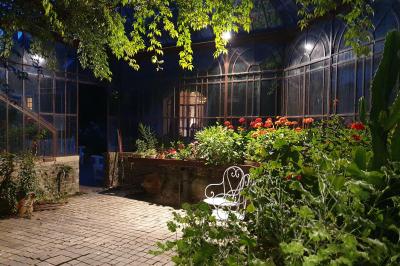 Miniature Location salle Verderonne (Oise) - Domaine de Verderonne #25 Serre illuminée au crépuscule, entourée de murs en pierre et d'arbres, avec une tour en arrière-plan.