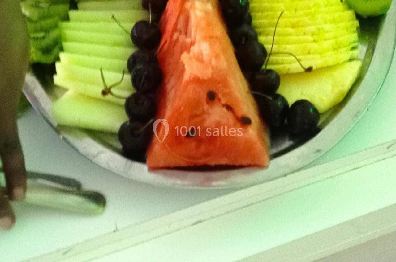 Plateau de fruits variés avec pastèque, ananas, mangue, kiwi, raisins et cerises, disposés de manière décorative.