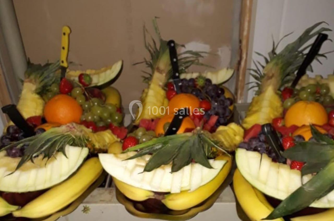 Plateaux de fruits frais composés de bananes, ananas, raisins, fraises, oranges et pastèques, décorés avec des couteaux.