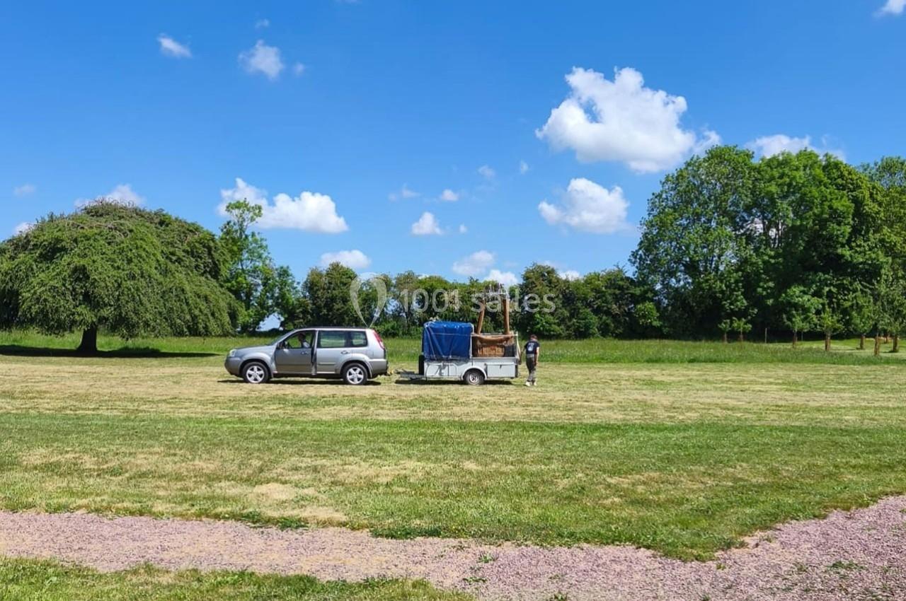 Un véhicule avec une remorque contenant un ballon à air chaud stationné dans un champ sous un ciel dégagé.