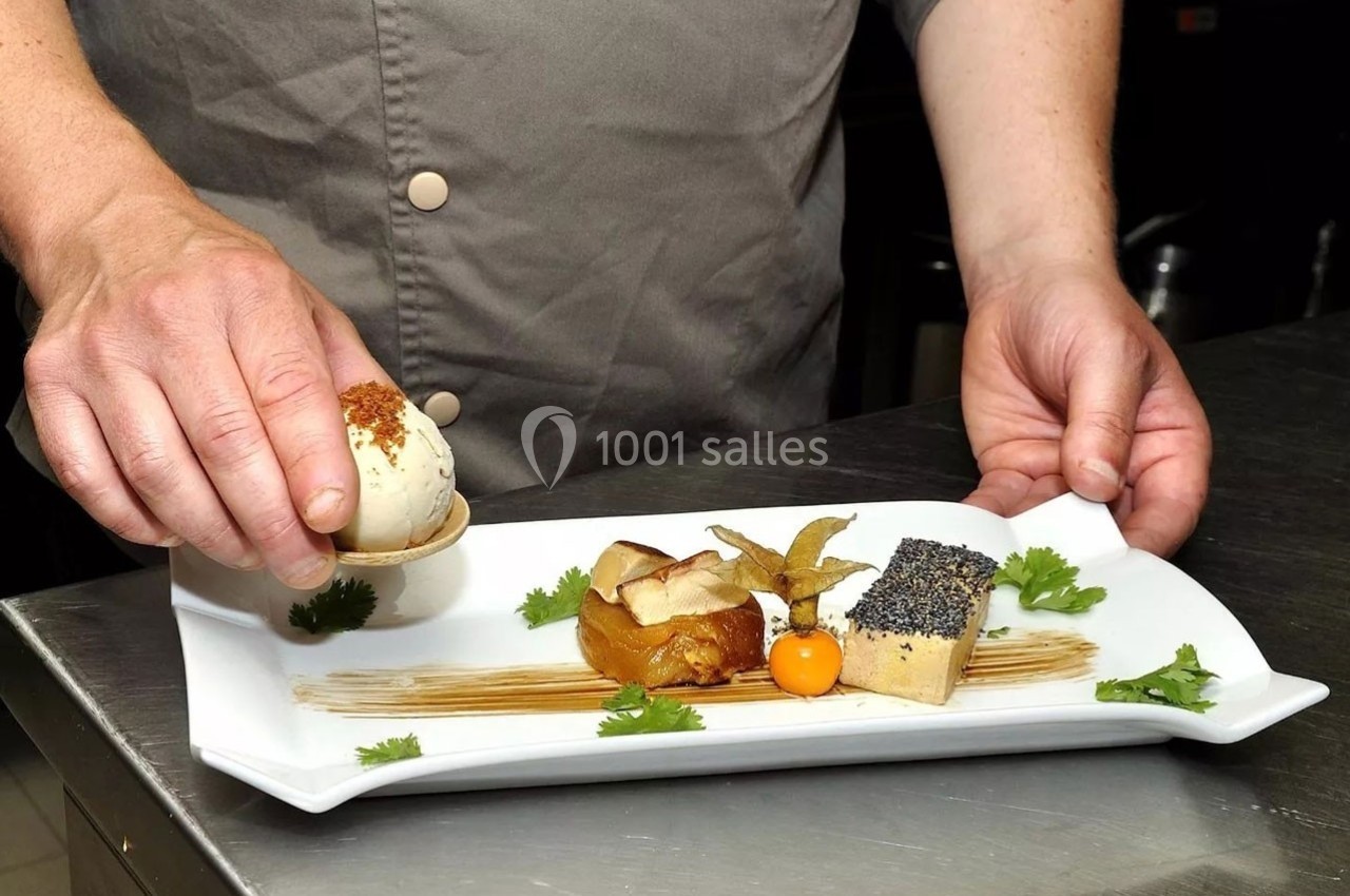 Un chef dispose un œuf garni sur une assiette gastronomique avec foie gras, purée et décoration soignée.