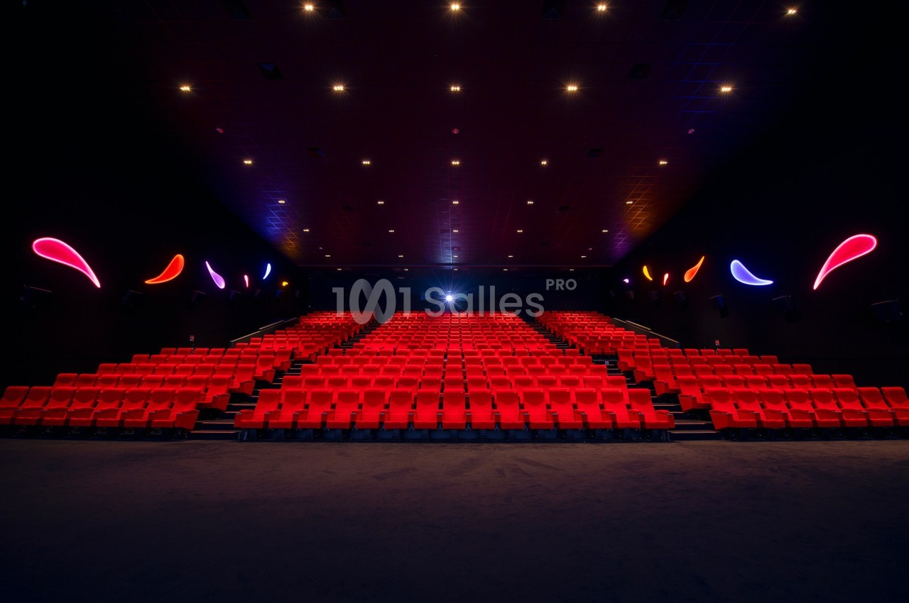 Salle de cinéma vide avec rangées de sièges rouges, éclairage tamisé et décorations lumineuses sur les murs.