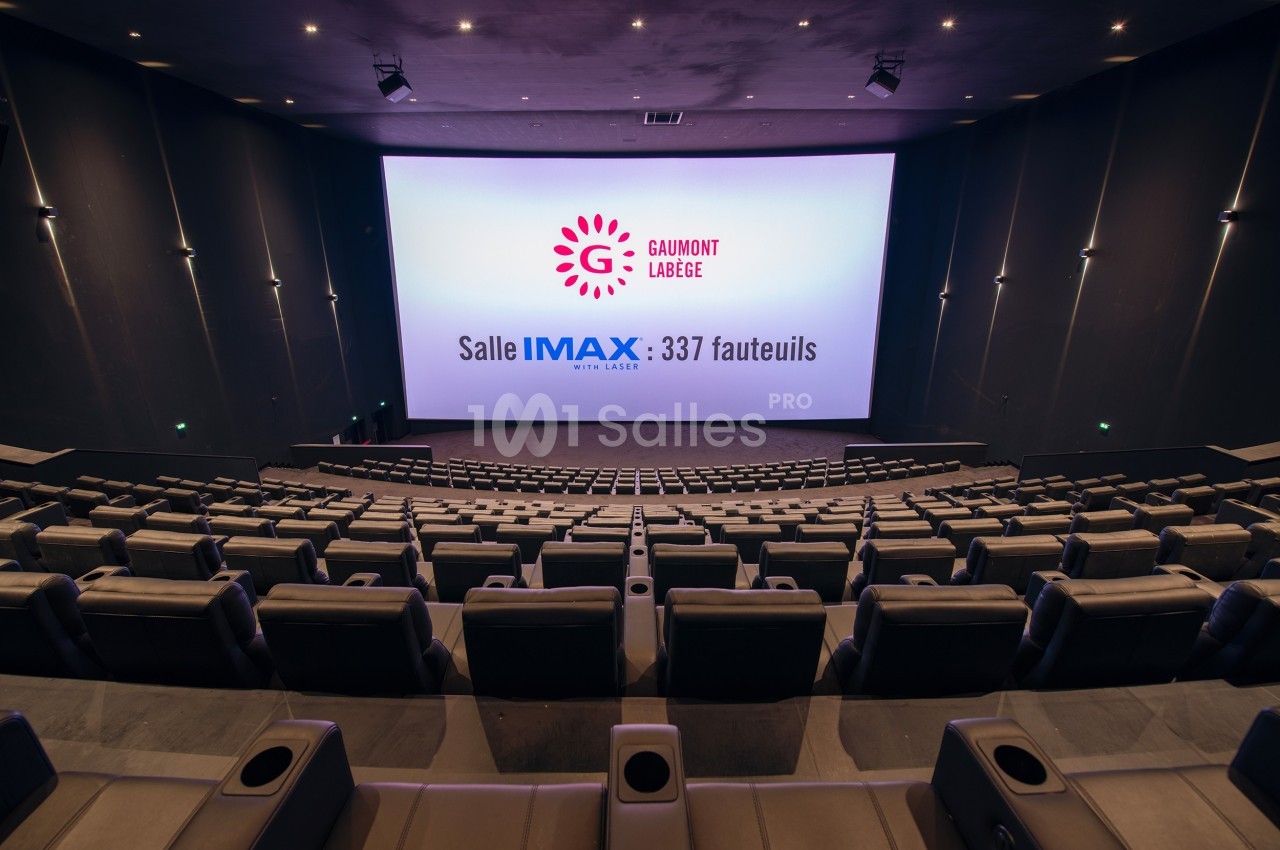 Salle de cinéma IMAX vide avec 337 fauteuils, écran géant et éclairage tamisé.