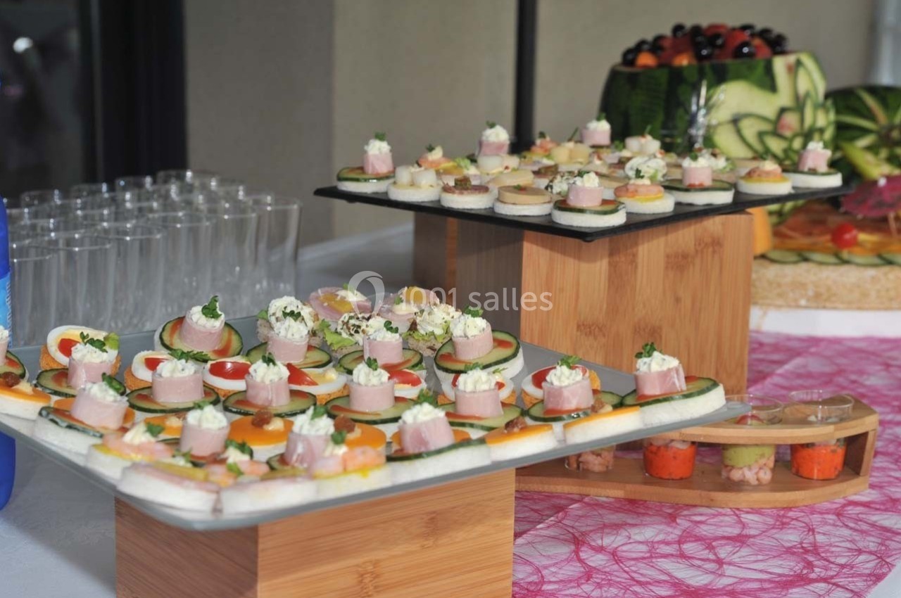 Plateaux de canapés variés avec légumes, fromage et charcuterie, présentés sur des supports en bois lors d'un buffet.