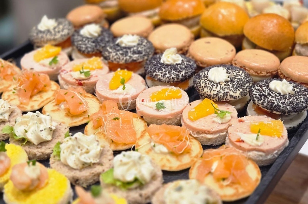 Plateau de bouchées apéritives variées comprenant mini-burgers, canapés au saumon et autres garnitures.