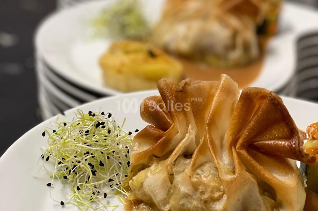 Feuilleté doré garni, accompagné de pousses germées et d'une garniture de légumes sur une assiette blanche.