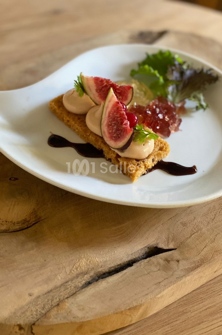 Dessert élégant composé de figues fraîches, mousse, gelée et salade verte, présenté sur une assiette blanche.
