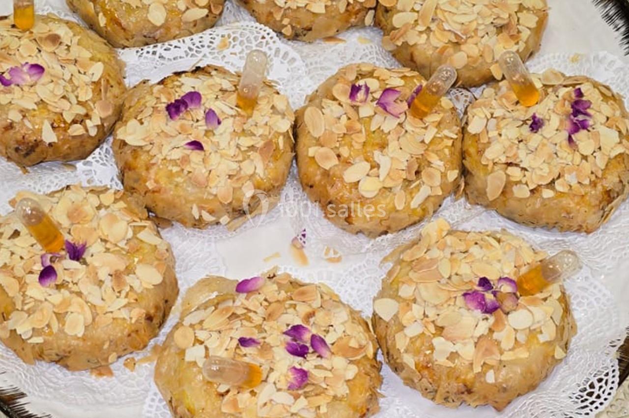 Pâtisseries garnies d'amandes effilées, décorées de fleurs comestibles et de pipettes contenant un liquide.
