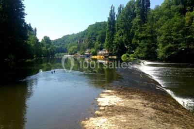 Salle de bain moderne avec carrelage gris, lavabo, toilettes et fenêtre laissant entrer la lumière naturelle.