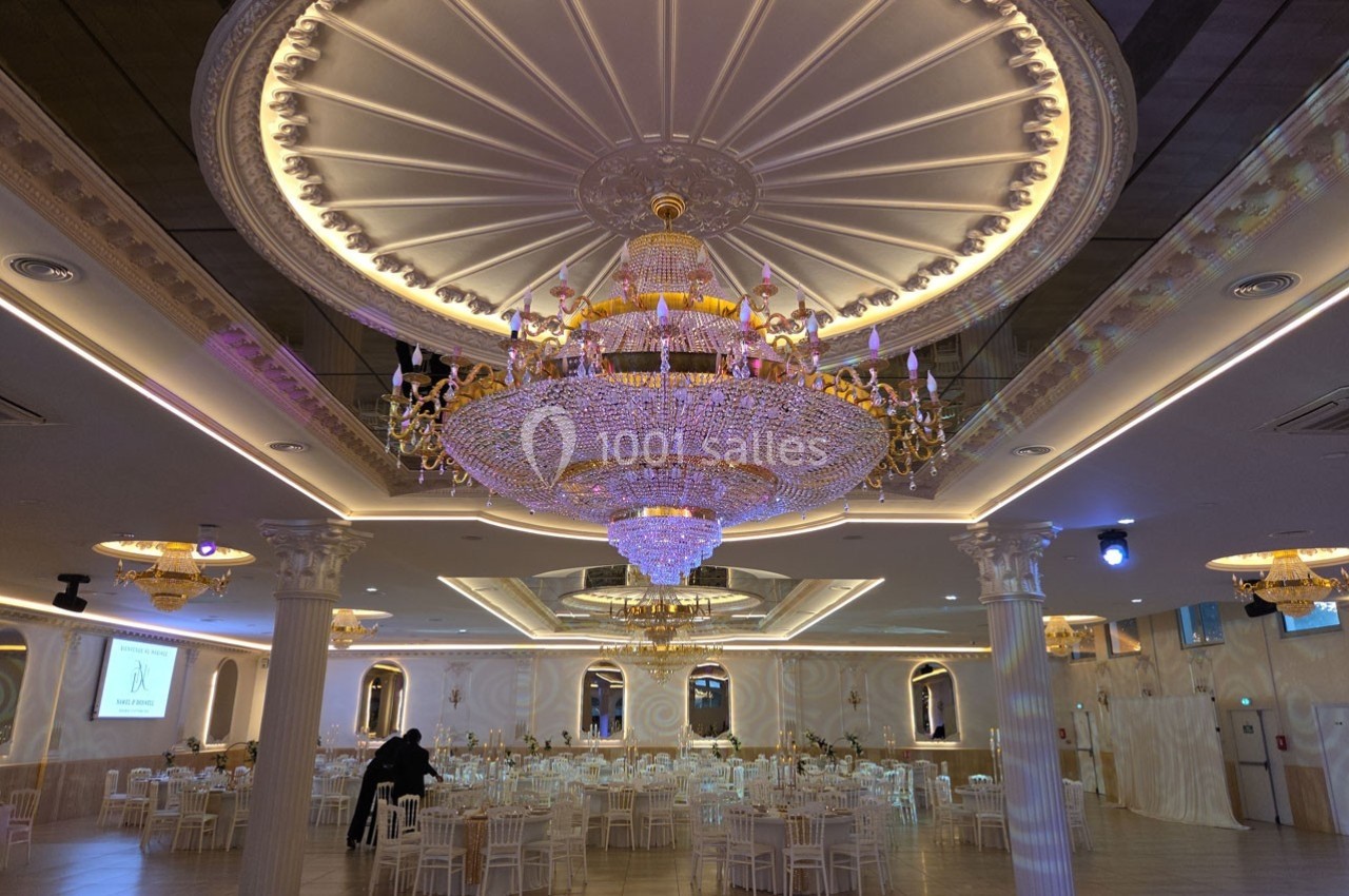 Salle de réception élégante avec de grands lustres en cristal, tables dressées et décorations raffinées.
