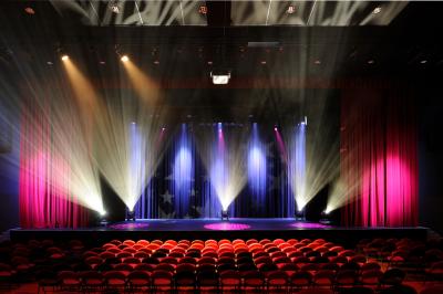 Salle de réception avec tables dressées, verres alignés au premier plan et décorations florales en arrière-plan.
