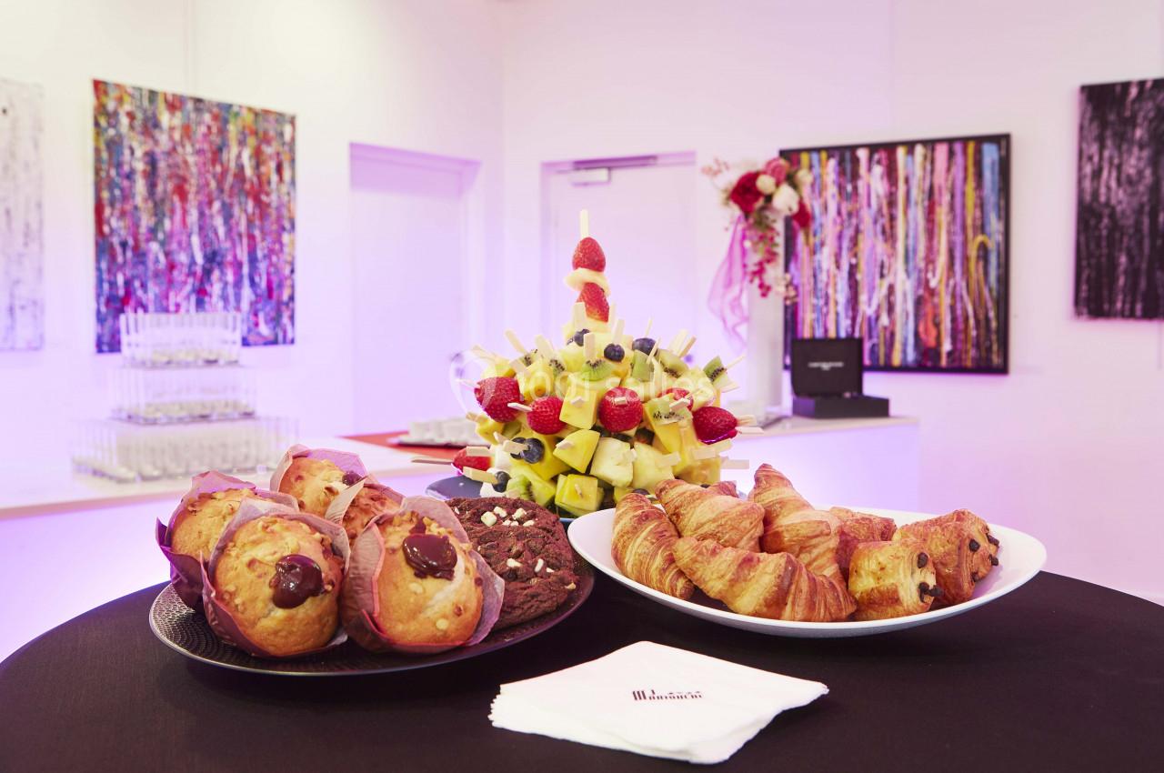 Location salle La Grande-Motte (Hérault) - Pasino de la Grande Motte #3 Assortiment de viennoiseries, muffins et brochettes de fruits sur une table dans une salle décorée de tableaux colorés.
