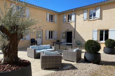 Chambre lumineuse avec lit double, armoire, téléviseur sur table et fenêtre donnant sur un extérieur verdoyant.
