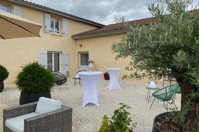 Chambre lumineuse avec lit double, armoire, téléviseur sur table et fenêtre donnant sur un extérieur verdoyant.