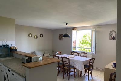 Chambre lumineuse avec lit double, armoire, téléviseur sur table et fenêtre donnant sur un extérieur verdoyant.
