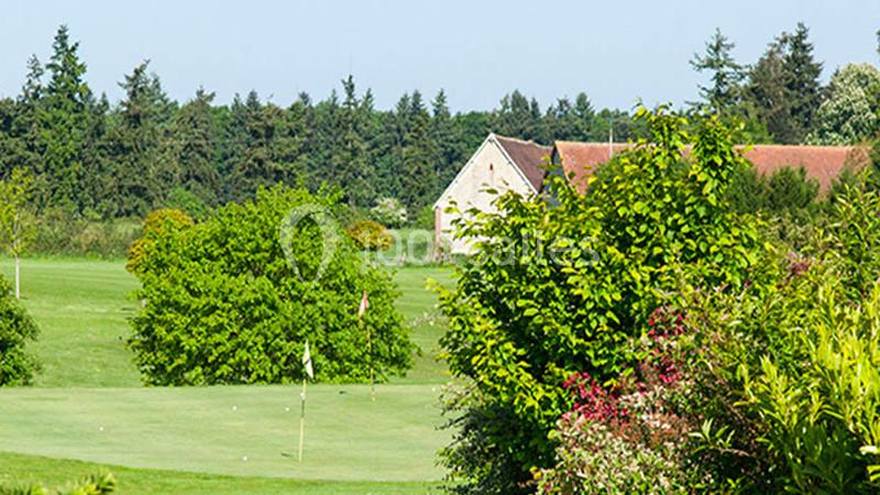 Paysage de golf avec un green entouré de végétation luxuriante et une maison en arrière-plan.