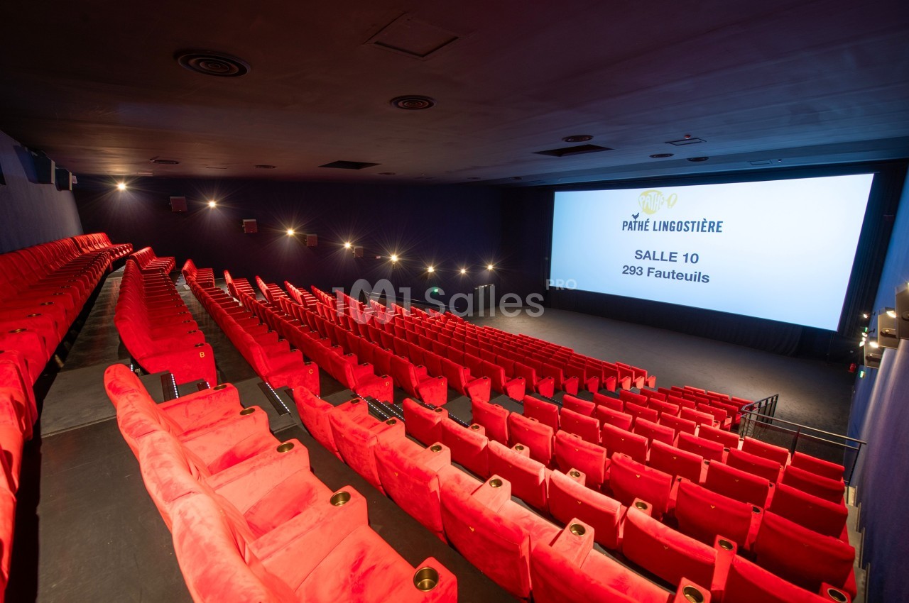 Salle de cinéma avec des rangées de fauteuils rouges vides et un écran affichant des informations sur la salle.