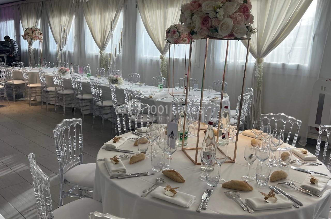 Location salle Beauchamp (Val-d'Oise) - Les Salons Beauchamp #27 Salle de réception décorée avec des tables rondes dressées, chaises transparentes et centres de table fleuris.