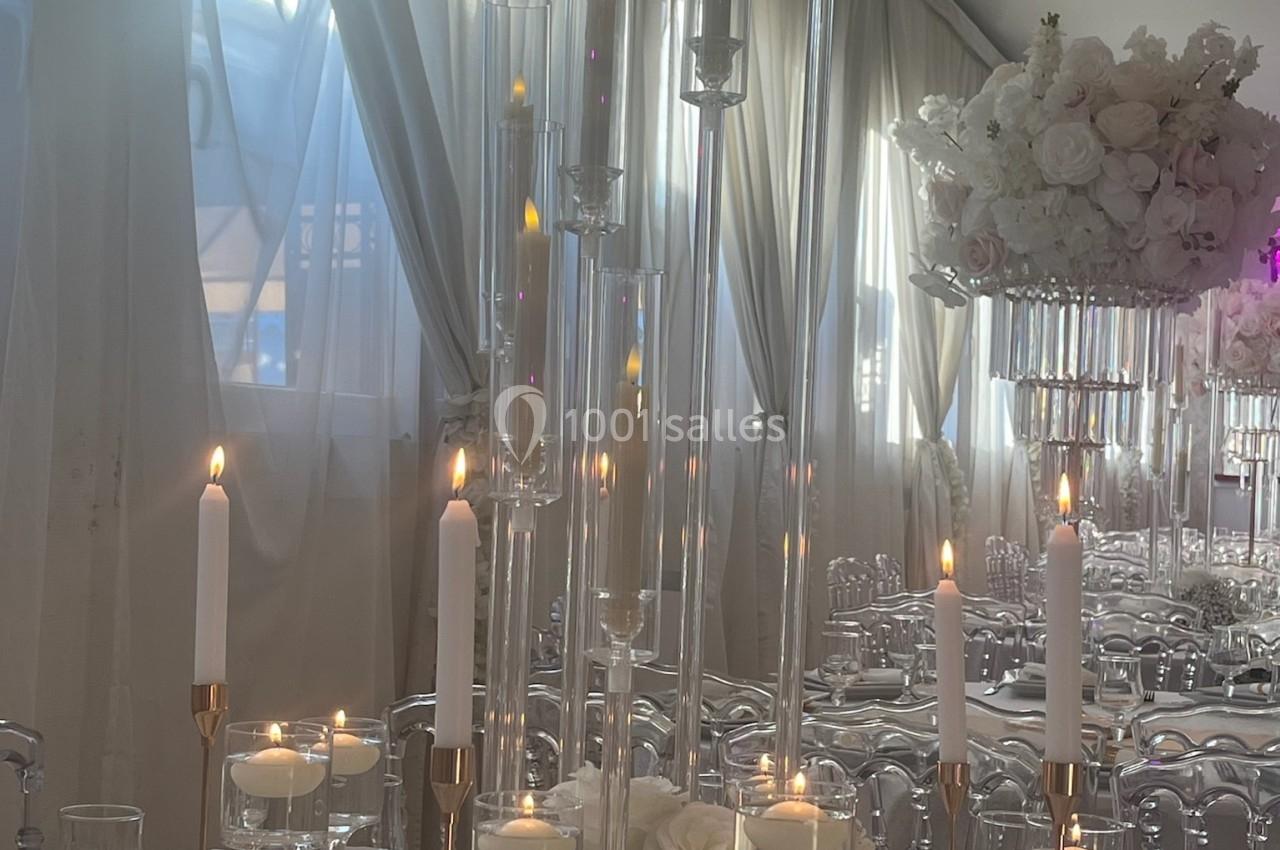 Location salle Beauchamp (Val-d'Oise) - Les Salons Beauchamp #46 Bougies allumées et décorations florales blanches sur une table élégamment dressée dans une salle lumineuse.