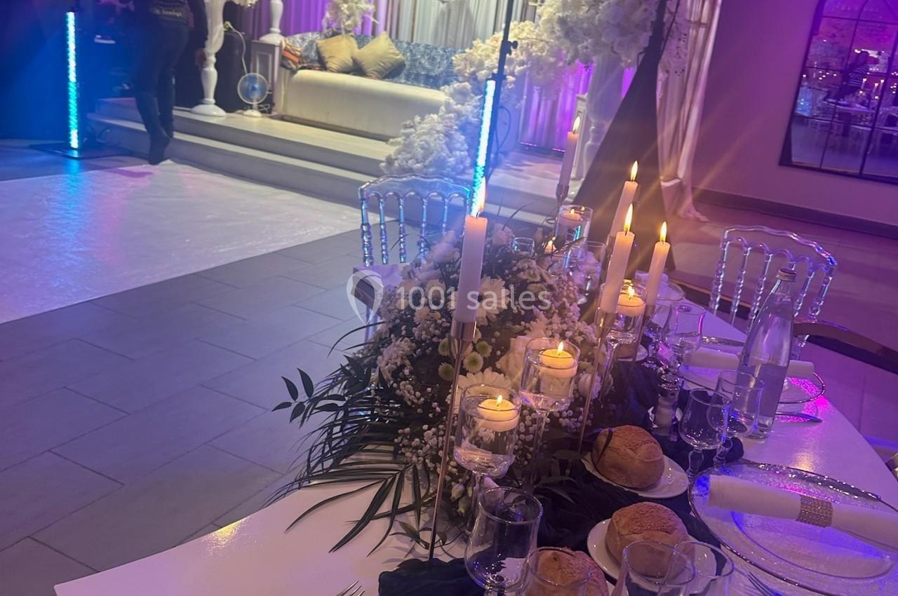 Location salle Beauchamp (Val-d'Oise) - Les Salons Beauchamp #24 Table élégamment dressée avec bougies et décor floral, en arrière-plan un espace lounge décoré pour un événement festif.